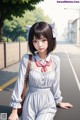 A girl in a white dress sitting on the side of a road.