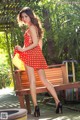 A woman in a red polka dot dress sitting on a bench.