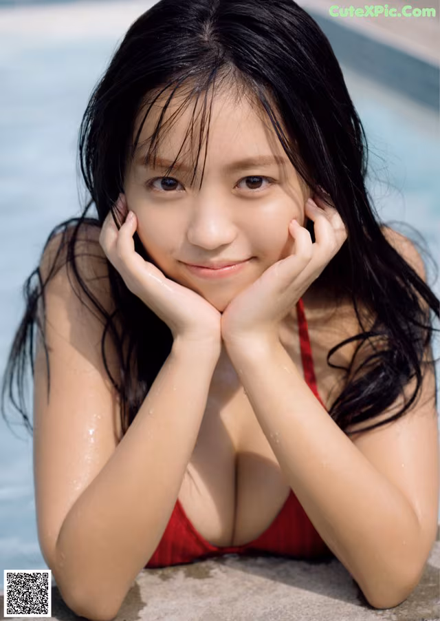 A woman in a red bathing suit laying by a pool.