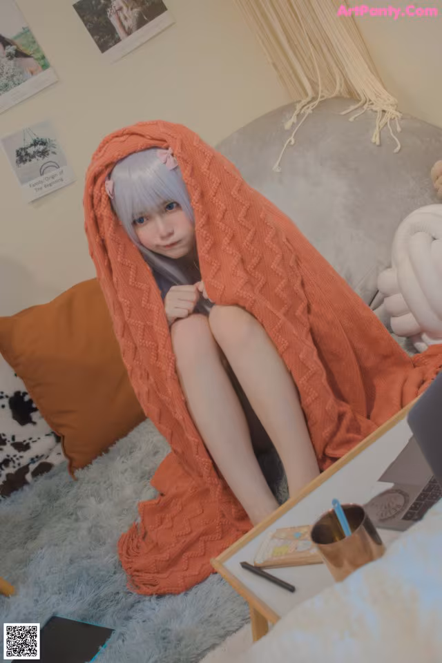 A woman sitting on a couch wrapped in a blanket.