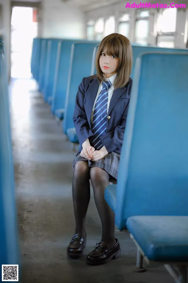 A woman in a school uniform sitting on a train.
