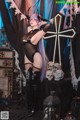 A woman dressed as a demon posing in front of a cross.