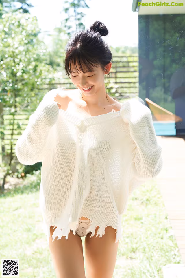 A woman in a white sweater is walking in the grass.