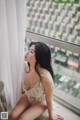 A woman sitting on a window sill looking out a window.