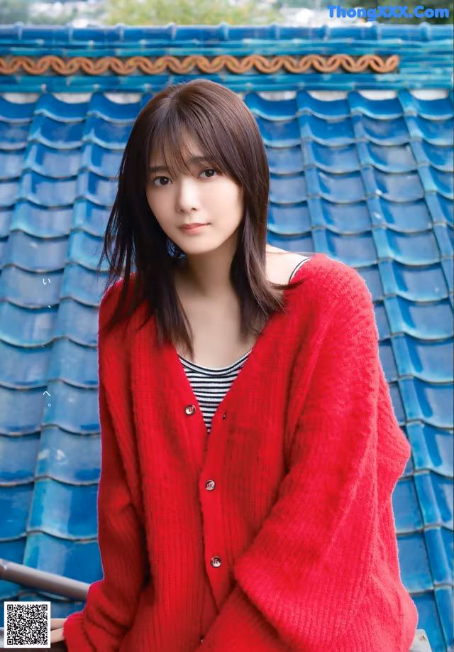 A woman in a red cardigan is posing for a picture.