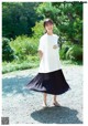 A woman wearing a white shirt and a black pleated skirt.