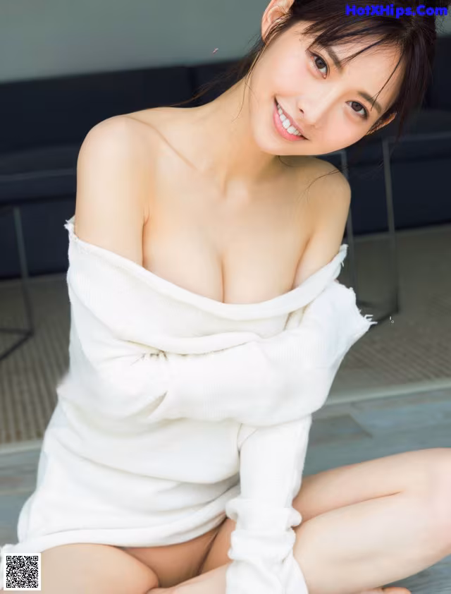 A woman in a white sweater sitting on the floor.