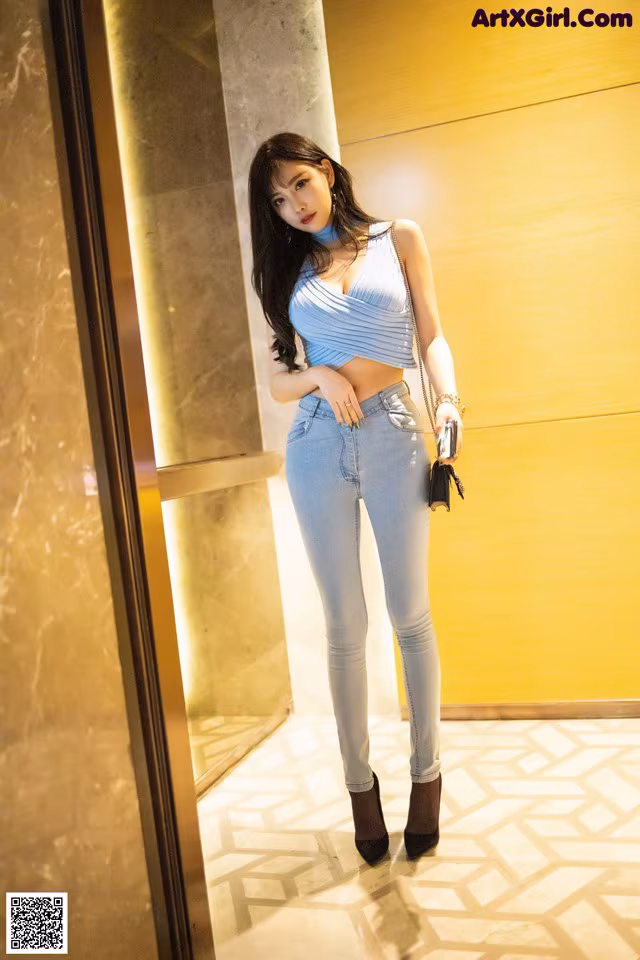 A woman standing in front of an elevator holding a purse.