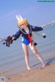 A woman in a bunny costume holding a gun on the beach.