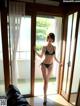 A woman in a bikini standing in front of a sliding glass door.