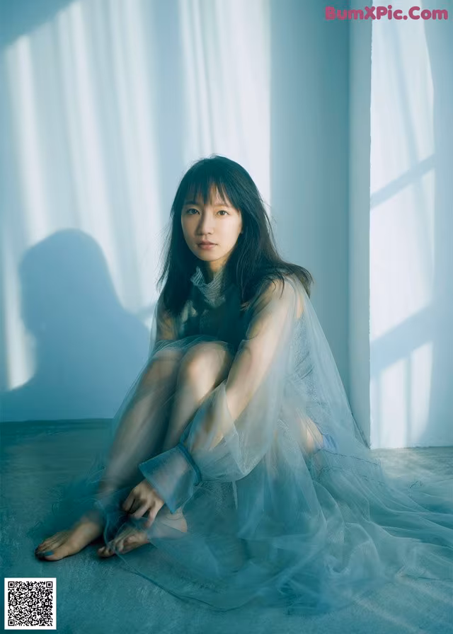 A woman sitting on the floor in a blue dress.