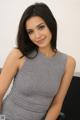 A woman in a gray dress sitting on a black chair.