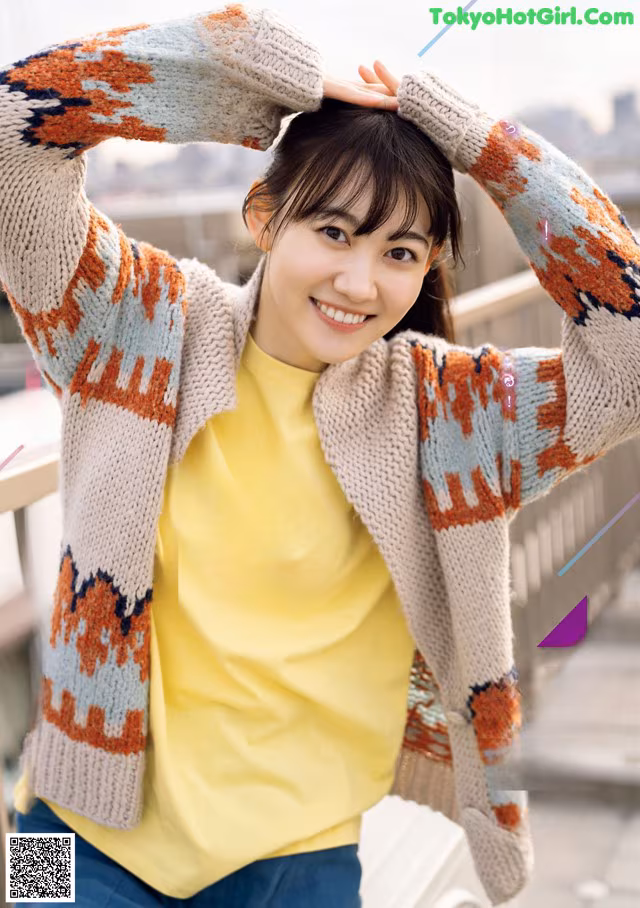 A woman wearing a yellow shirt and a colorful cardigan.