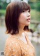 A woman in an orange dress is looking away from the camera.