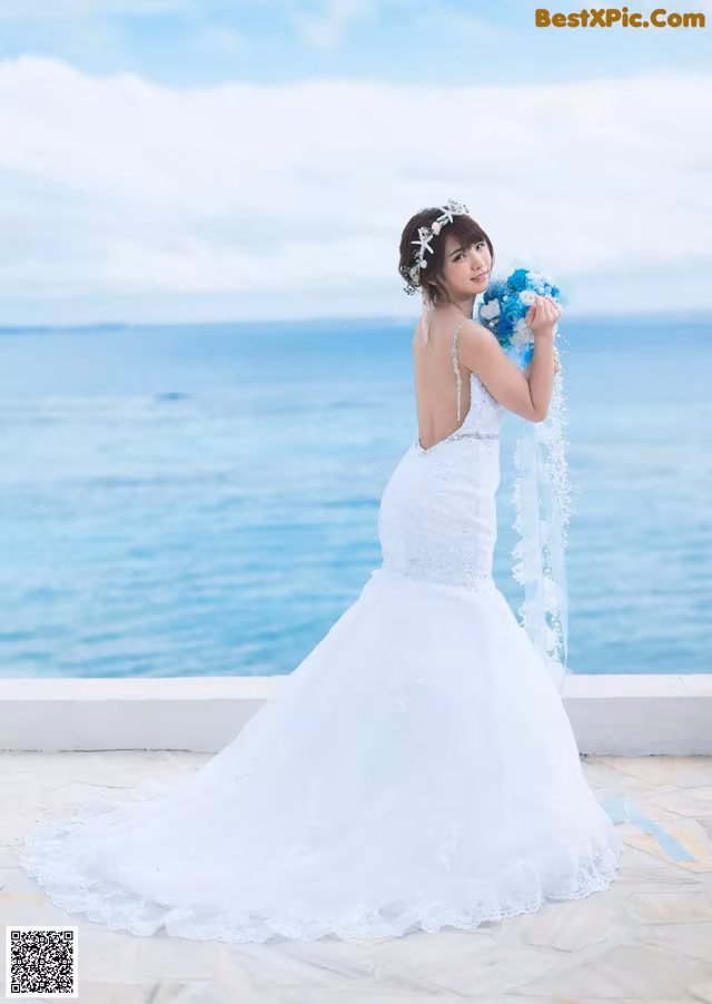 A woman in a wedding dress holding a bouquet of flowers.